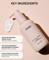 OUAI Anti-Frizze Creme bottle in a pale pink shade, shown with a white cream swirl on a matching pale pink background. The image includes text overlays detailing key ingredients like squalane from olives and upcycled jackfruit and beetroot extract.