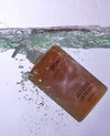 OUAI hair product being submerged in water with a white background