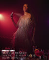 A woman stands in a dimly lit club-like setting wearing a sparkling fringe dress under red and purple lighting, holding a spray bottle. Text at the bottom reads, 'SMELLS LIKE: DINNER AT MIDNIGHT, DANCING THE NIGHT A-QUAL, YOU'RE DATING A DJ'.