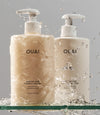 OUAI Medium Hair shampoo and conditioner bottles splashed with water droplets