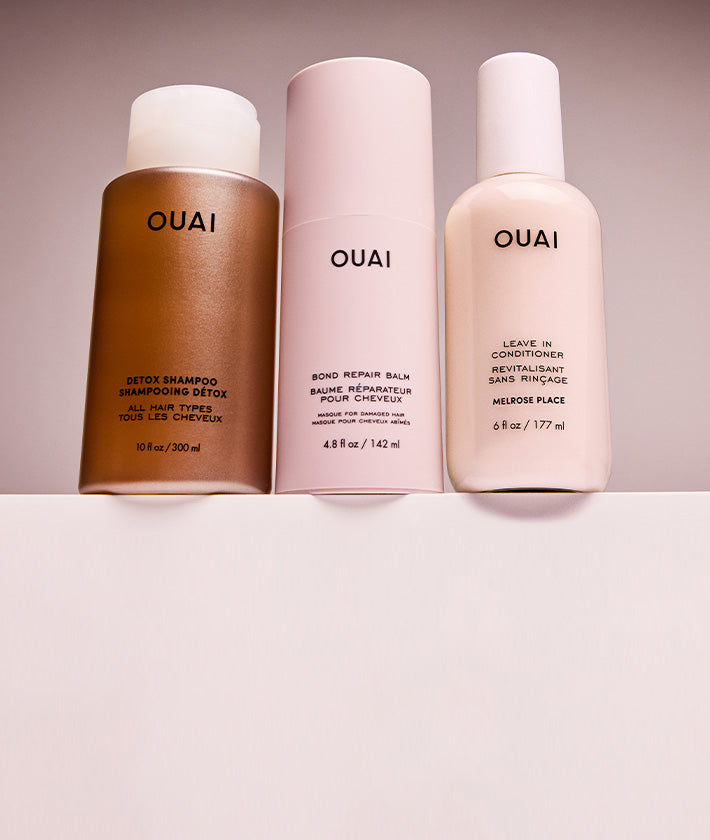 ouai detox shampoo, bond repair balm and leave in conditioner bottles on a neutral background