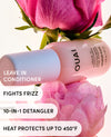 OUAI leave-in conditioner bottle shown diagonally on pink flowers, with text overlays reading 'LEAVE IN CONDITIONER', 'FIGHTS FRIZZ', '10-IN-1 DETANGLER', and 'HEAT PROTECTS UP TO 450°F'.
