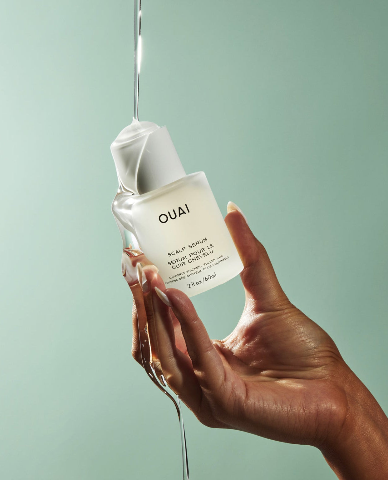 OUAI Scalp Serum bottle held by hand with serum dripping down