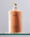 OUAI Thick Hair Shampoo 16oz bottle covered in lather on glass shelf