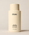 An ivory OUAI Fine Hair Conditioner bottle stands upright on a softly lit cream studio surface. Text: “OUAI”, “FINE HAIR”, “CHEVEUX FINS”, “CONDITIONER”, “REVITALISANT”, “10 fl oz / 300 ml”.