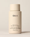An ivory OUAI Hair Gloss bottle stands upright against a warm neutral background. Text: “OUAI”, “HAIR GLOSS”, “BRILLANT À CHEVEUX”, “PROTECT COLOR & TREAT DAMAGE”, “PROTÈGE LA COULEUR ET TRAITE LES DOMMAGES”, “6 fl oz / 177 ml”.