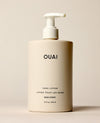 An ivory OUAI Dean Street Hand Lotion pump bottle stands upright on a softly lit cream surface. Text: “OUAI”, “HAND LOTION”, “LOTION POUR LES MAINS”, “DEAN STREET”, “16 fl oz / 474 ml”.