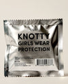 OUAI Knotty Girls Wear Protection silver foil hair tie packet on neutral background